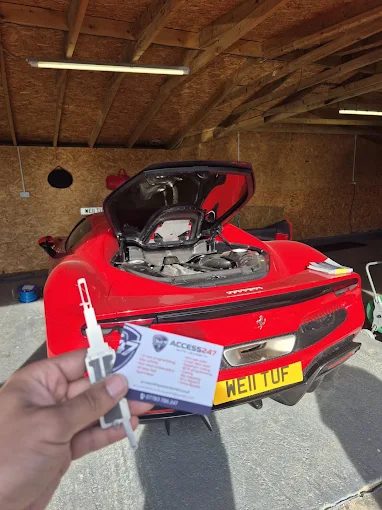 A newly cut and programmed key held in front of a red Ferrari